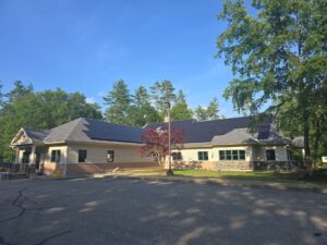 Commercial rooftop solar installation on a municipal building in Barrington, NH, featuring black solar panels installed by Porter Electrical Contracting.