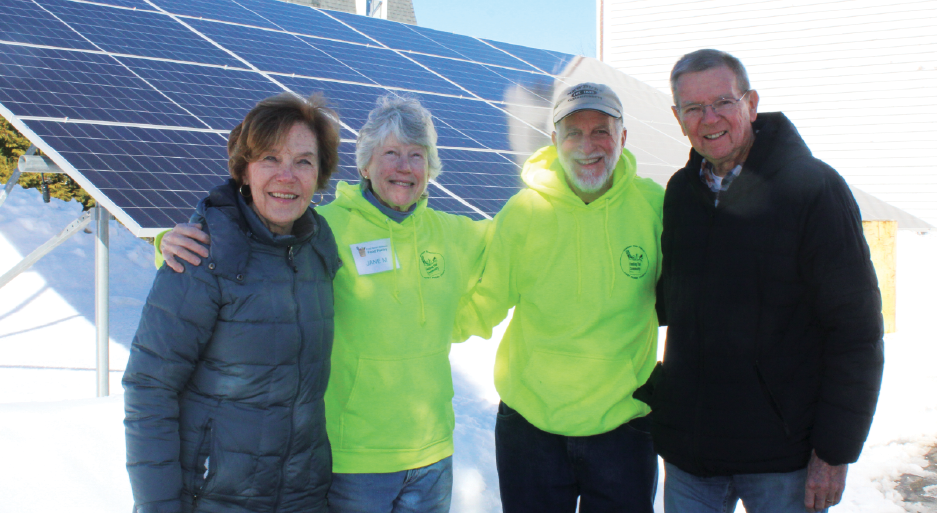 Community members standing in front of a ground-mounted solar panel installation in Newbury, MA, completed by Porter Electrical Contracting for a local church.