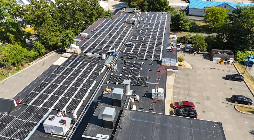 Aerial view of commercial rooftop solar panel installation on a warehouse in New Hampshire by Porter Electrical Contracting, providing solar for warehouses in NH.